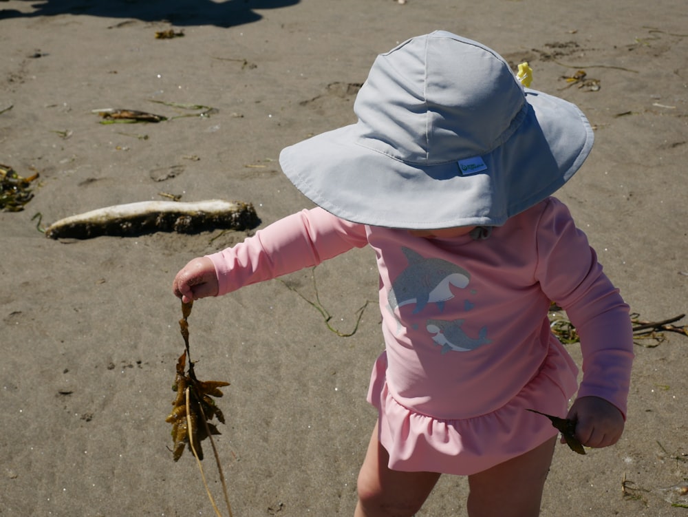 girl in pink dress and white hijab standing on beach shore during daytime