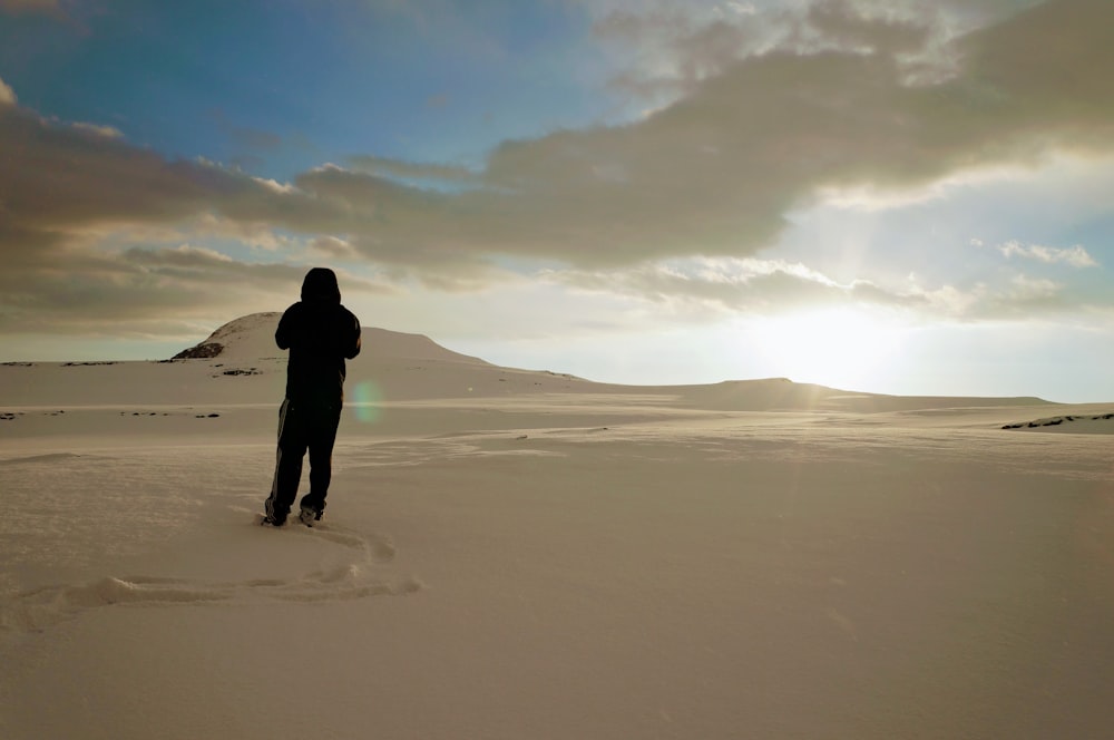 Person, die tagsüber auf weißem Sand spazieren geht