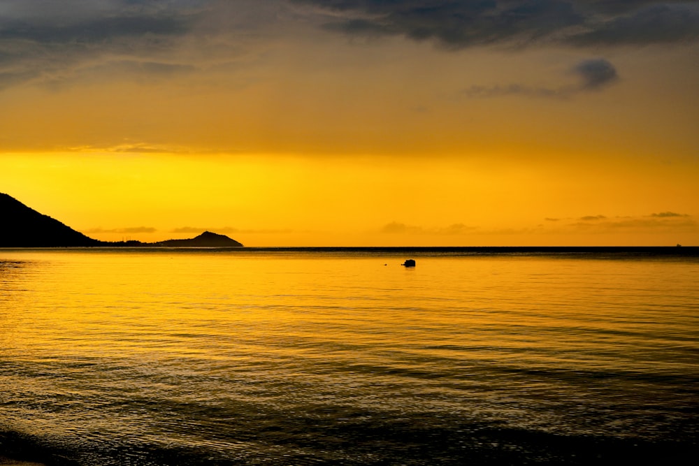 silhouette of mountain beside sea during sunset