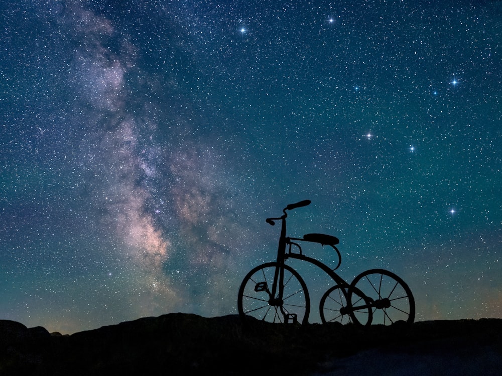 black mountain bike on black sand under blue sky during night time