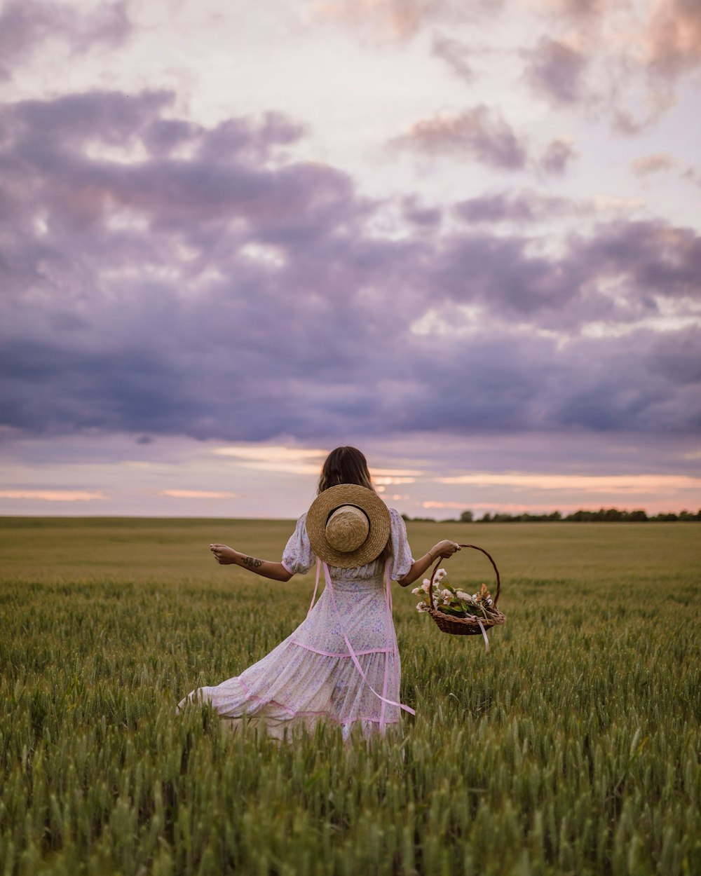 Frau in weißem Kleid sitzt tagsüber auf grünem Rasen unter bewölktem Himmel