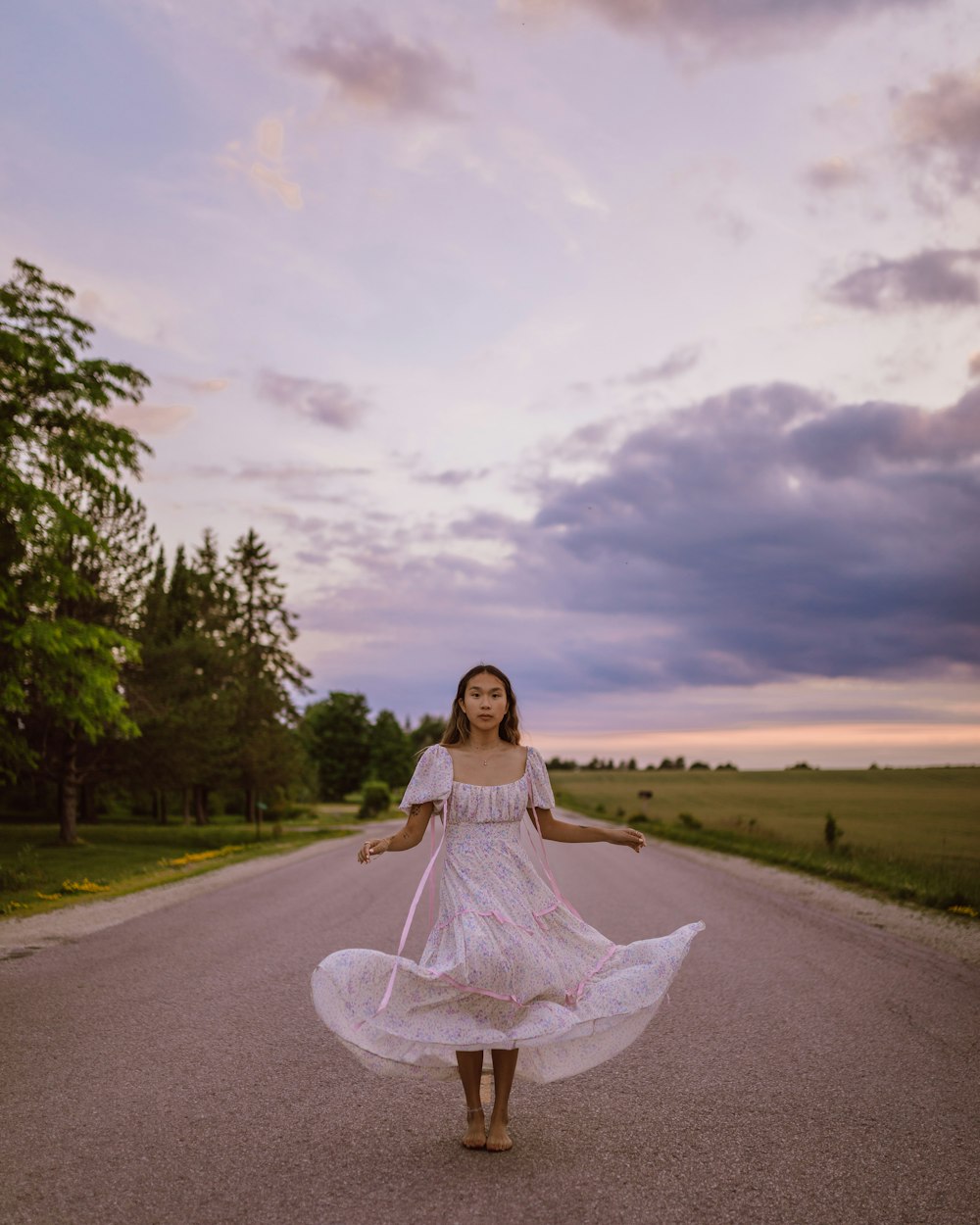 woman in white dress standing on road under gray clouds during daytime