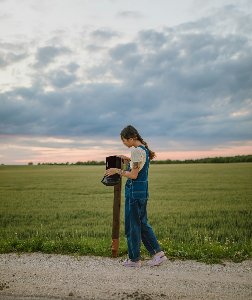 girl in blue and white stripe shirt and blue denim jeans standing on green grass field