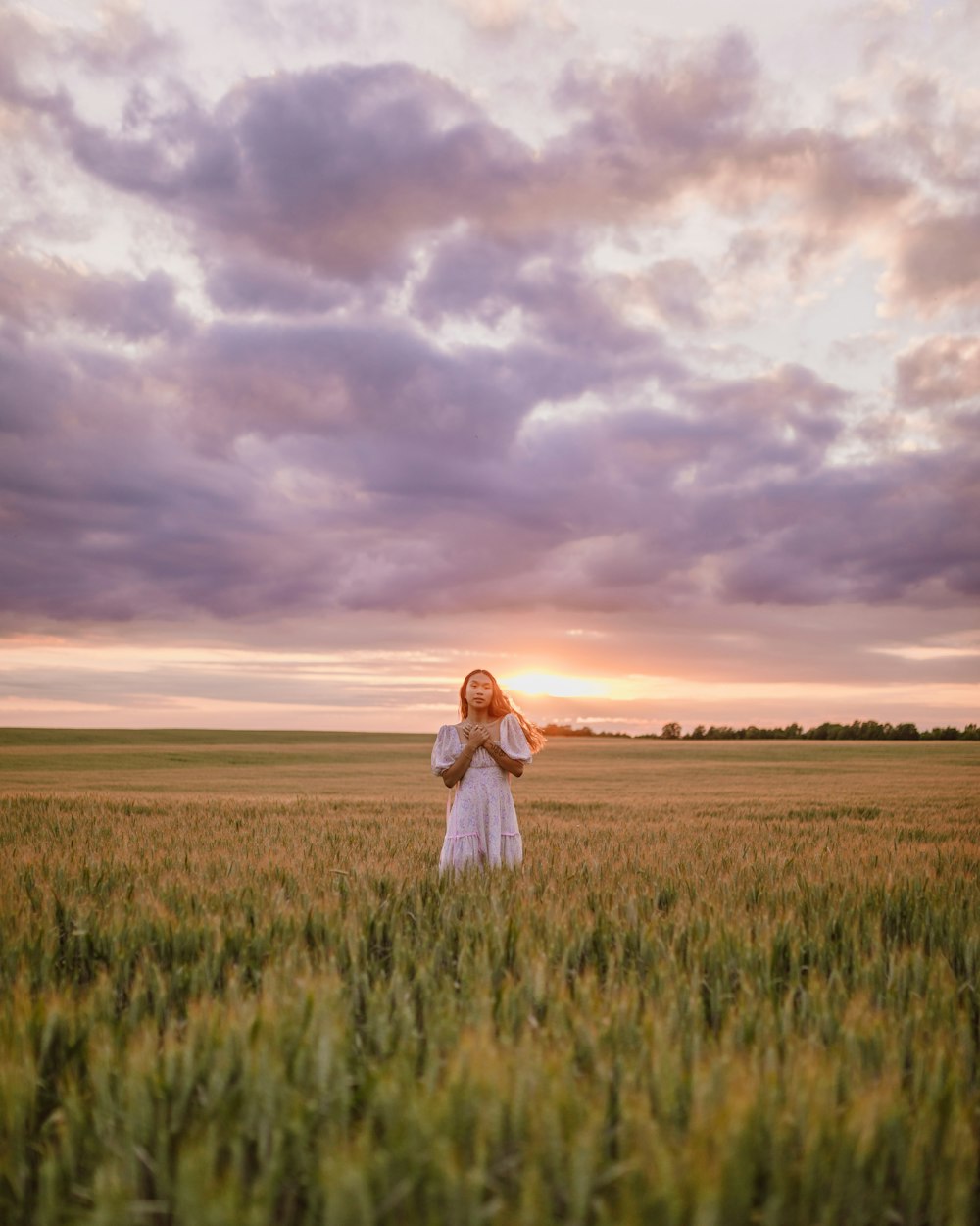 woman in white dress standing on green grass field under cloudy sky during daytime