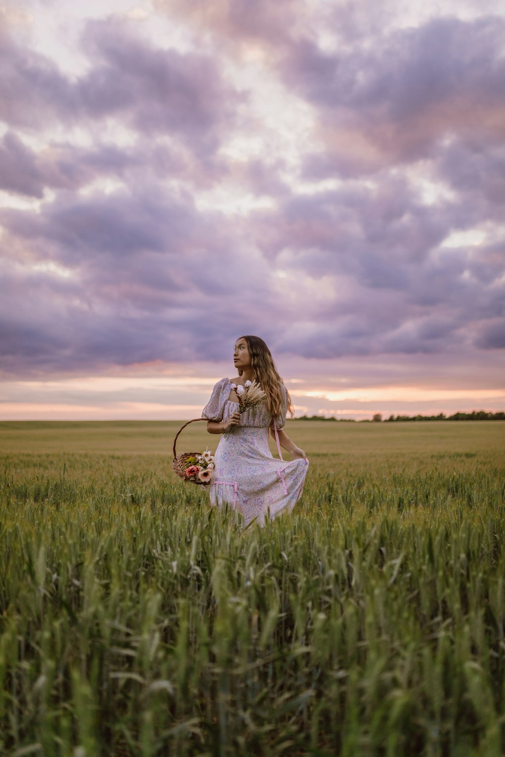 woman in white dress sitting on green grass field under cloudy sky during daytime