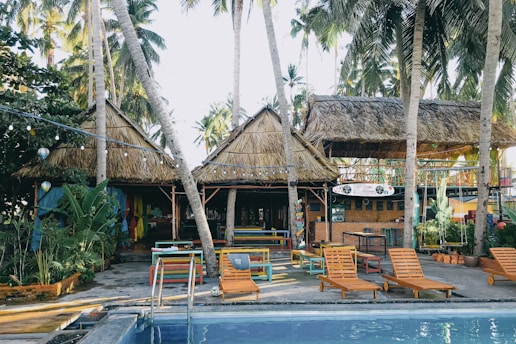 brown wooden lounge chairs near palm trees during daytime