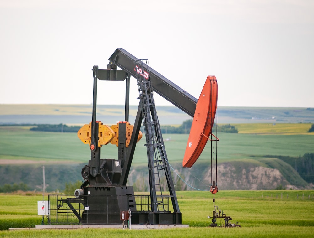 machine en métal noir et orange sur le terrain d’herbe verte pendant la journée