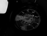 A close-up view of a speedometer displaying numbers in a range of 0 to 140 km/h. The needle is pointing slightly above 20 km/h. The odometer shows a reading of 21295.7 kilometers. The image is rendered in shades of black and white, which adds a dramatic and classic feel to the scene.
