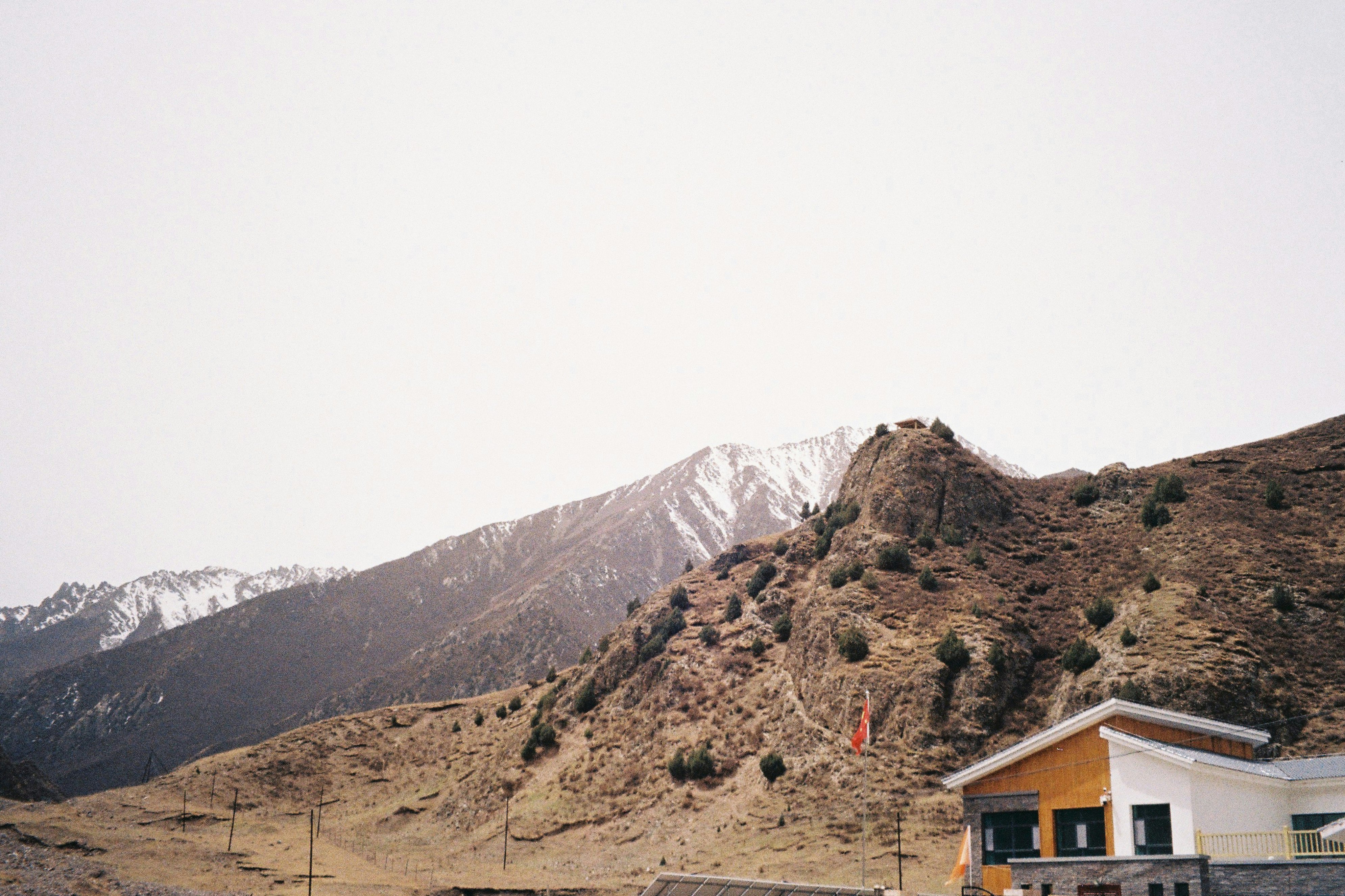 brown wooden house near snow covered mountain during daytime