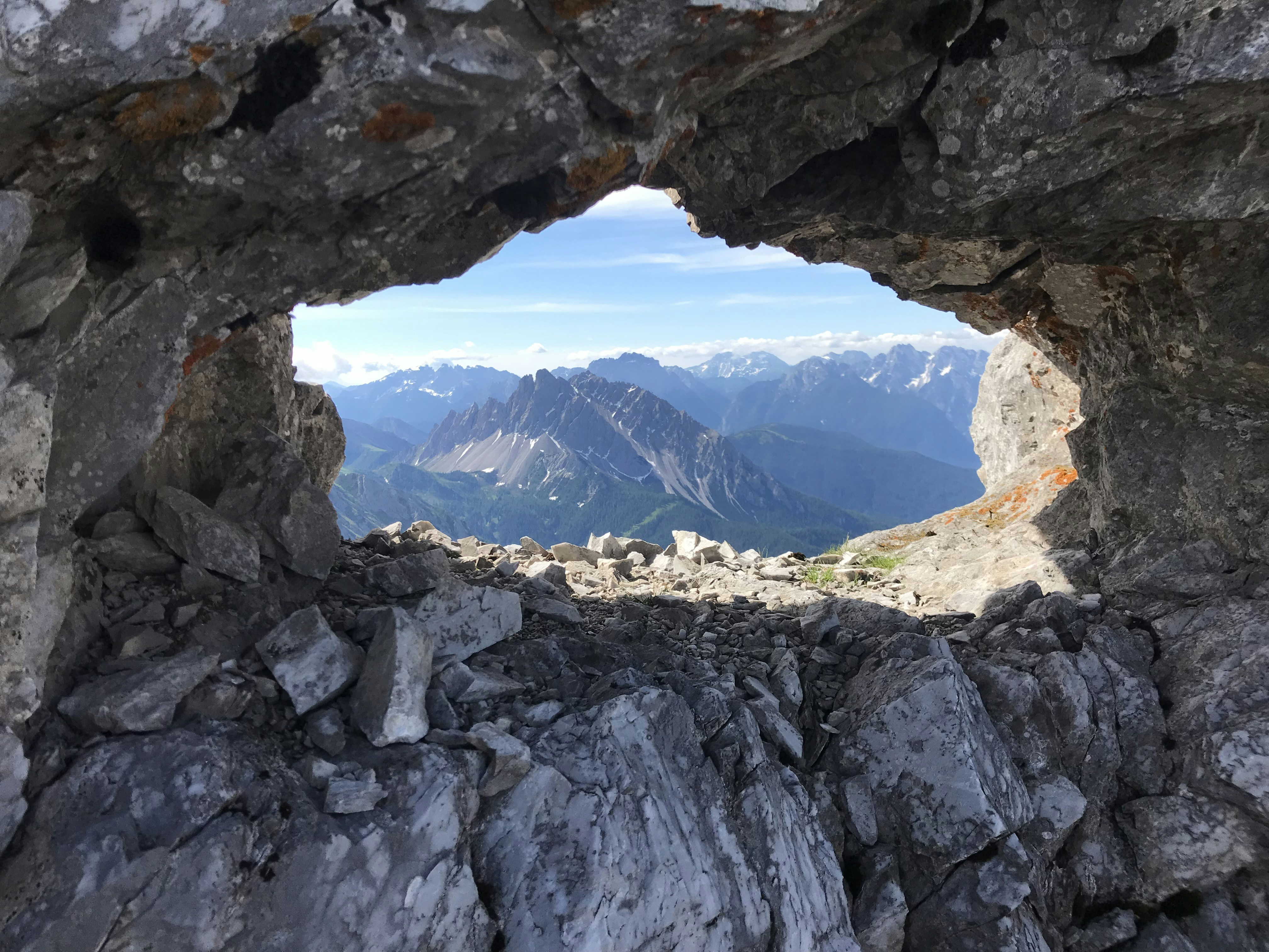 a hole in a rock wall with mountains in the background