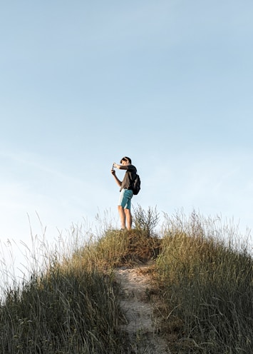 woman in black t-shirt and blue denim shorts standing on green grass field during daytime