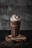 A tall glass of chocolate milkshake with whipped cream and a cherry on top.