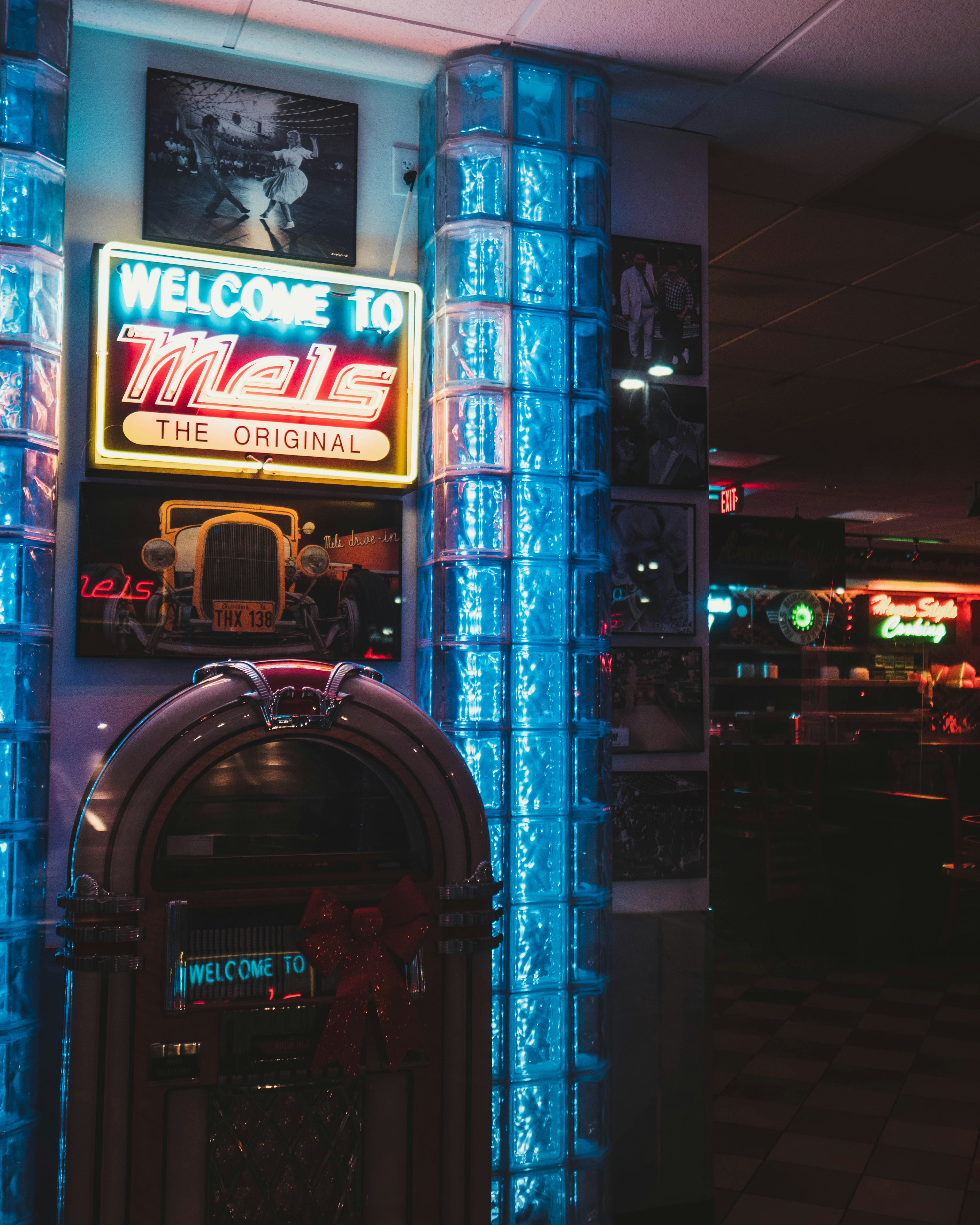 A jukebox lit by a neon display above it inside an otherwise low-lit bar.