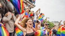 A joyful group photo celebrating LGBTQ+ pride with rainbow flags and inclusive smiles.