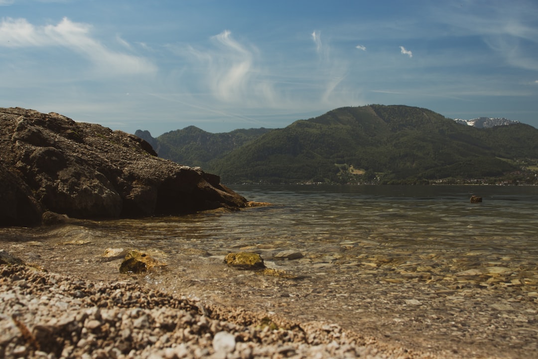 brown rocky mountain beside body of water during daytime