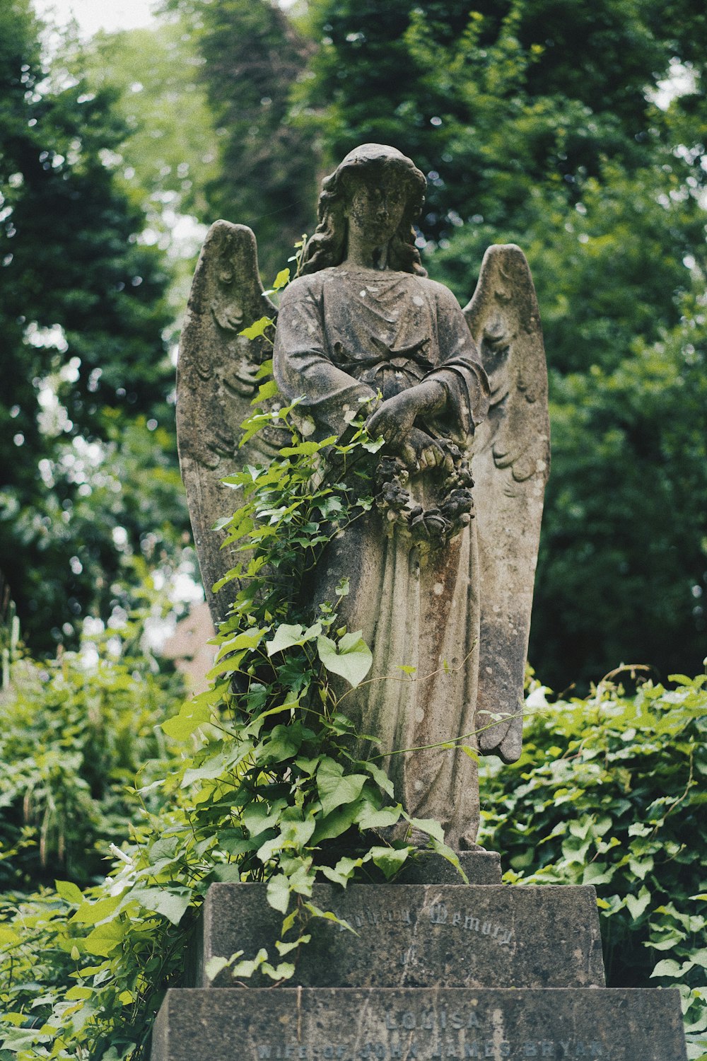 gray concrete statue near green trees during daytime