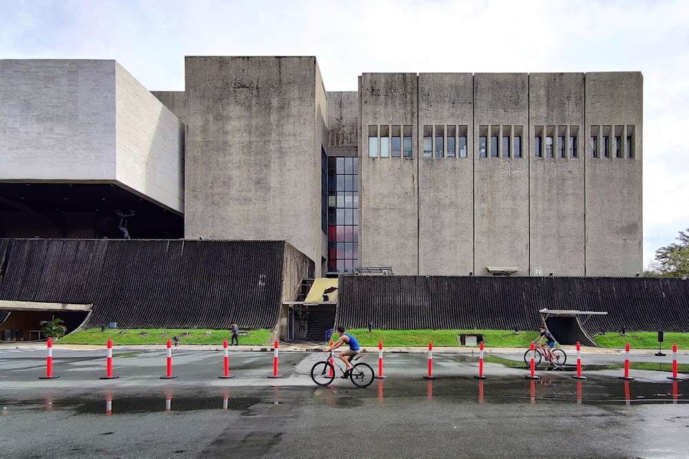 Bicicleta negra estacionada cerca de un edificio de concreto gris durante el día