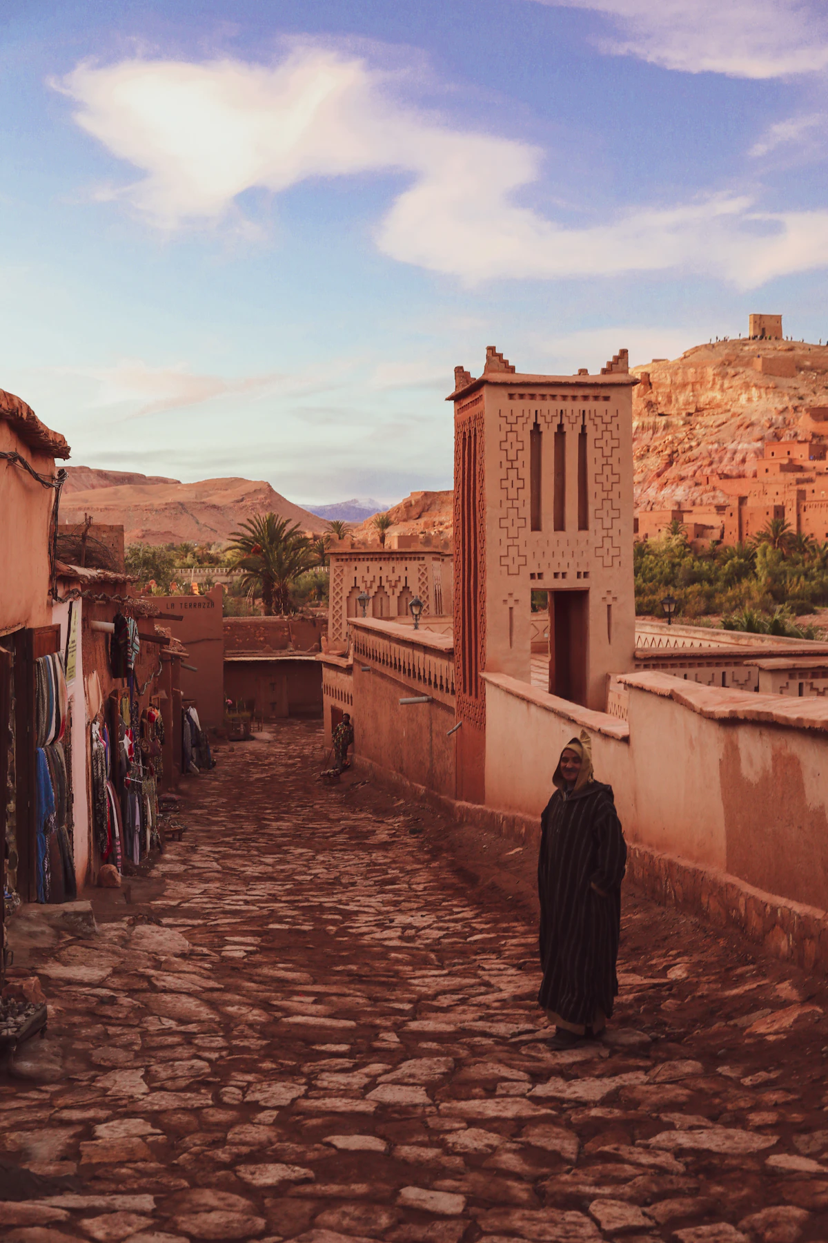 Walkers on a path near a brown kasbah, Morocco