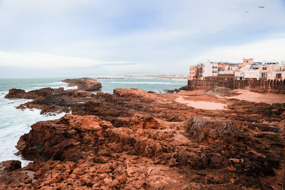 white concrete building on brown rock formation near body of water during daytime