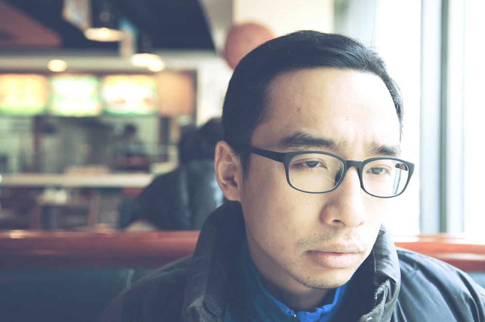 man in black framed eyeglasses and black jacket