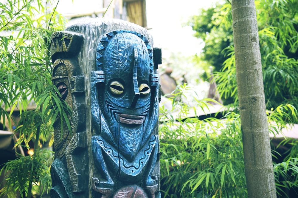 blue and black wooden human face carved statue