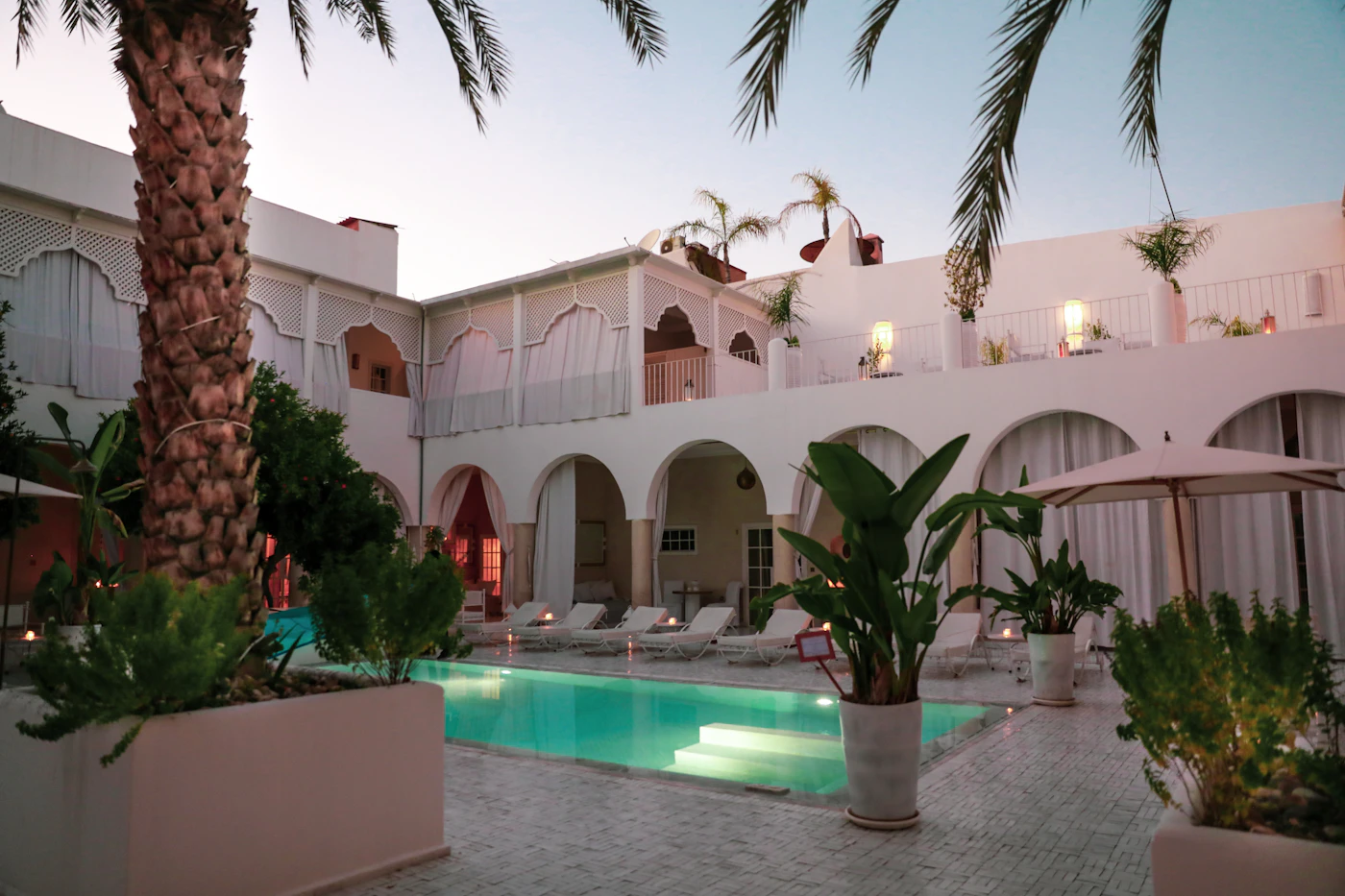 Riad blanc avec piscine et arcades mauresques au crépuscule