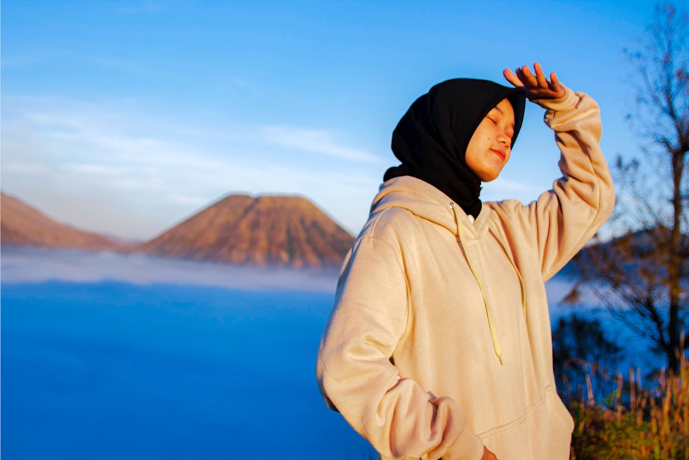 a man in a hoodie is standing by the water