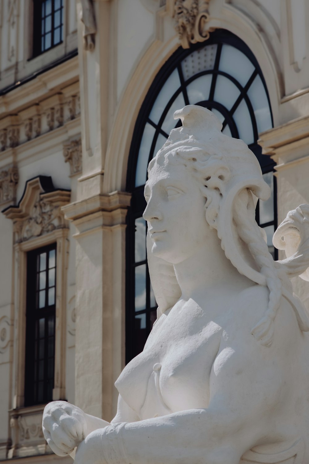 Weiße Betonstatue in der Nähe von schwarzem Metallzaun