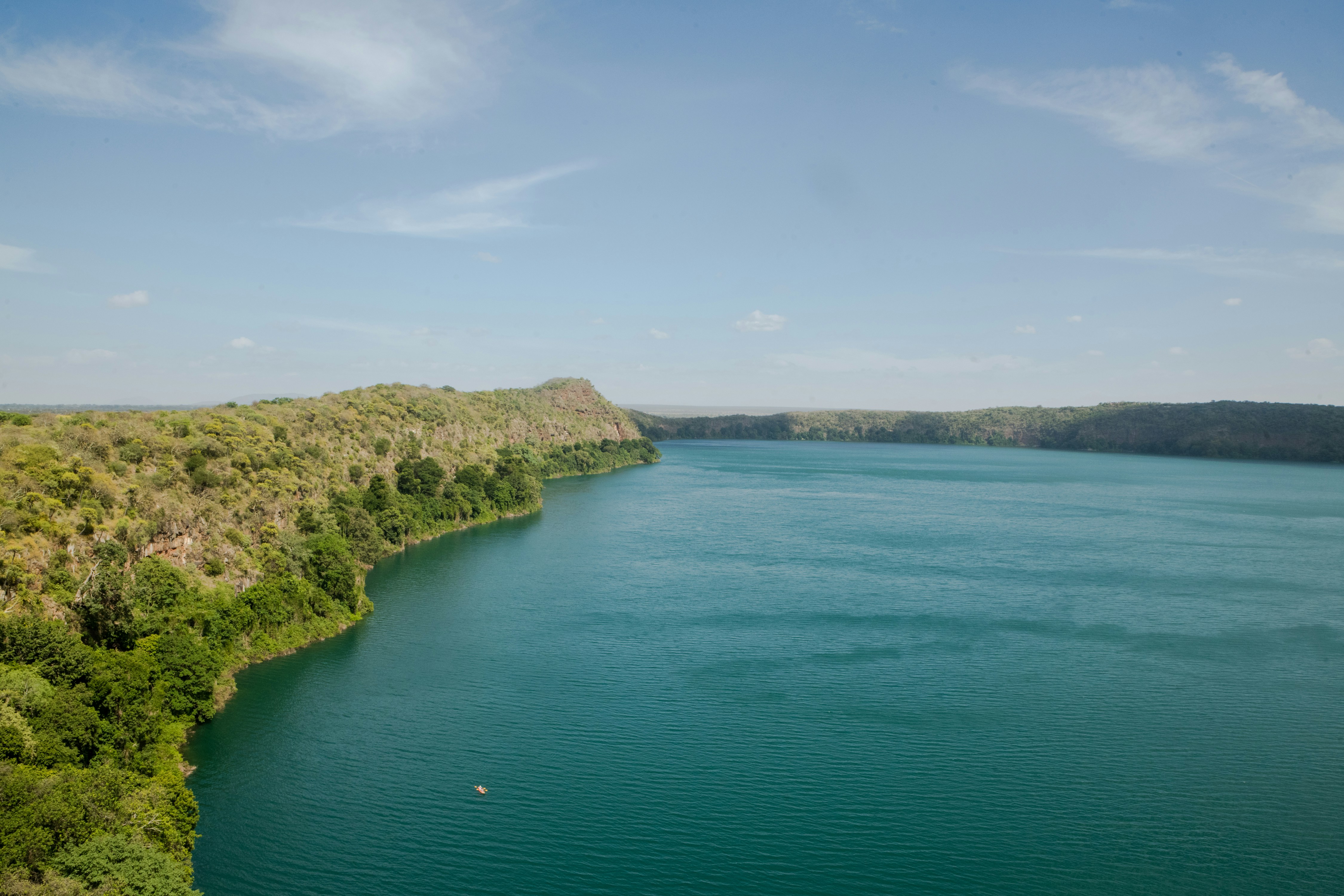 green and brown mountain beside body of water under blue sky during daytime