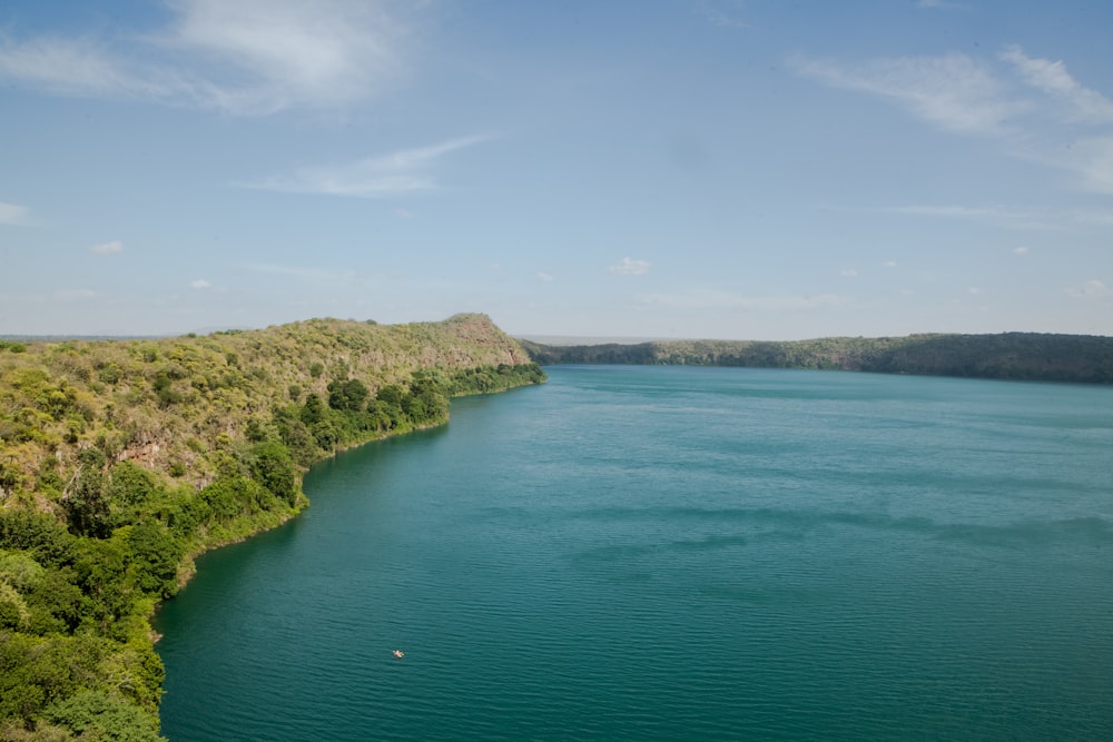 green and brown mountain beside body of water under blue sky during daytime