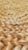 A close-up view of tightly woven natural fiber, likely jute or sisal, showcasing a braided pattern. The texture appears rough and tactile, with a natural sheen reflecting light.
