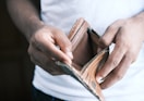 person holding brown leather bifold wallet