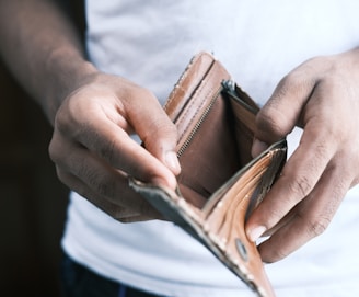 person holding brown leather bifold wallet