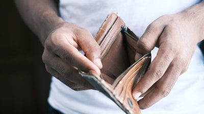 person holding brown leather bifold wallet