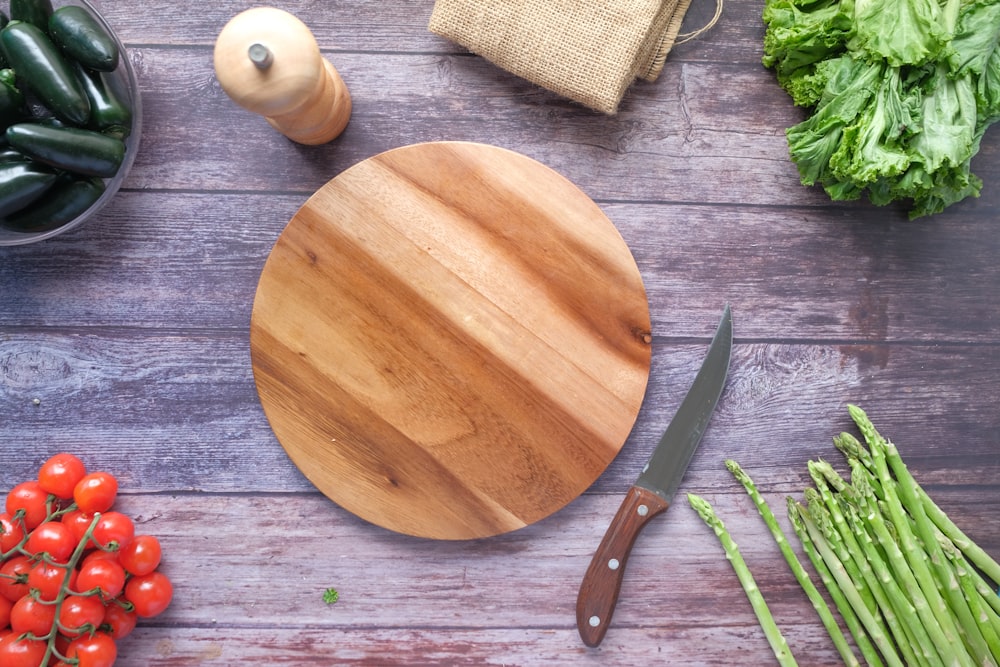 tábua de cortar madeira marrom ao lado de vegetal verde