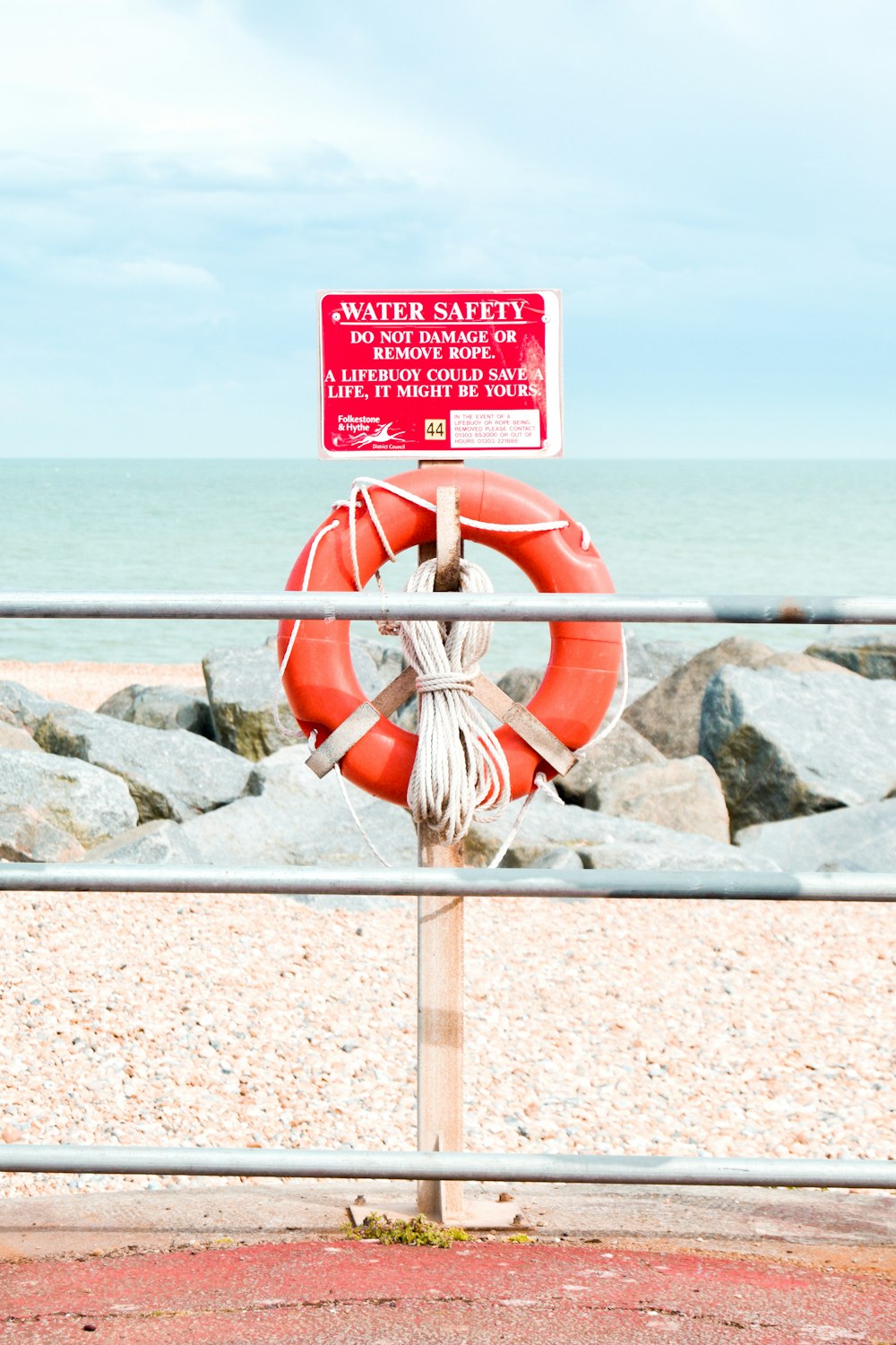 red and white inflatable ring on gray rock near sea during daytime