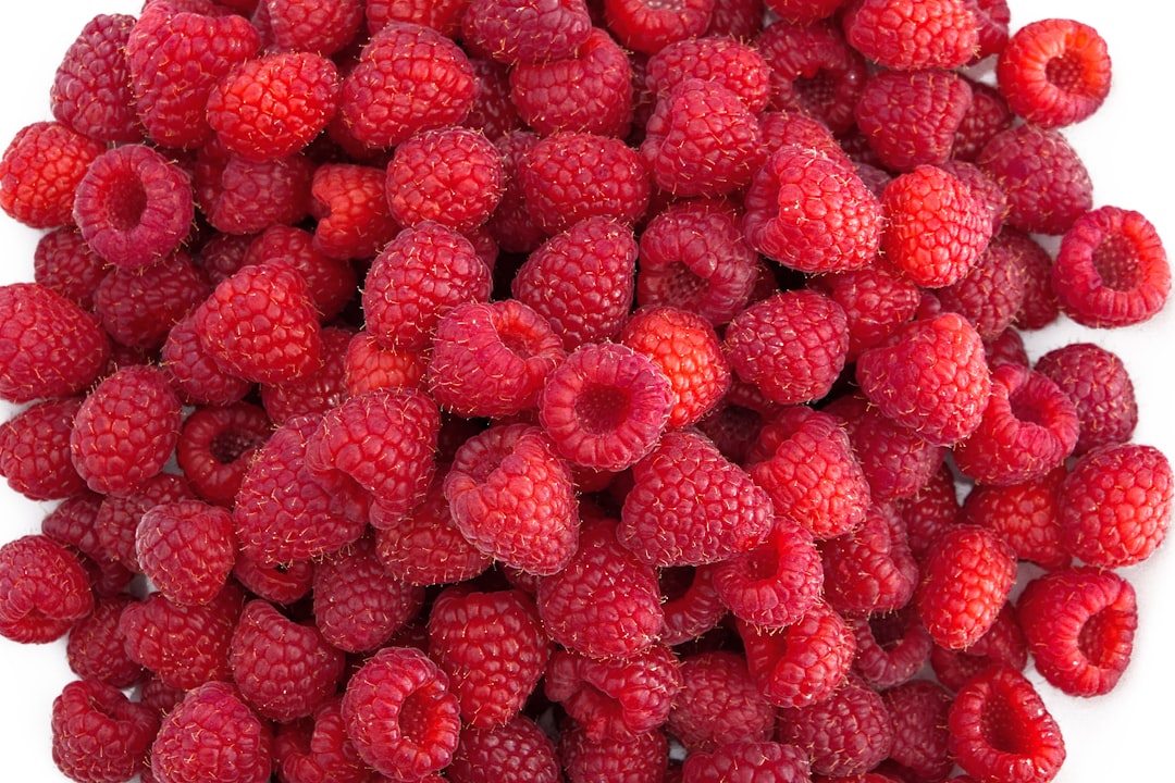 red raspberry fruits on white textile