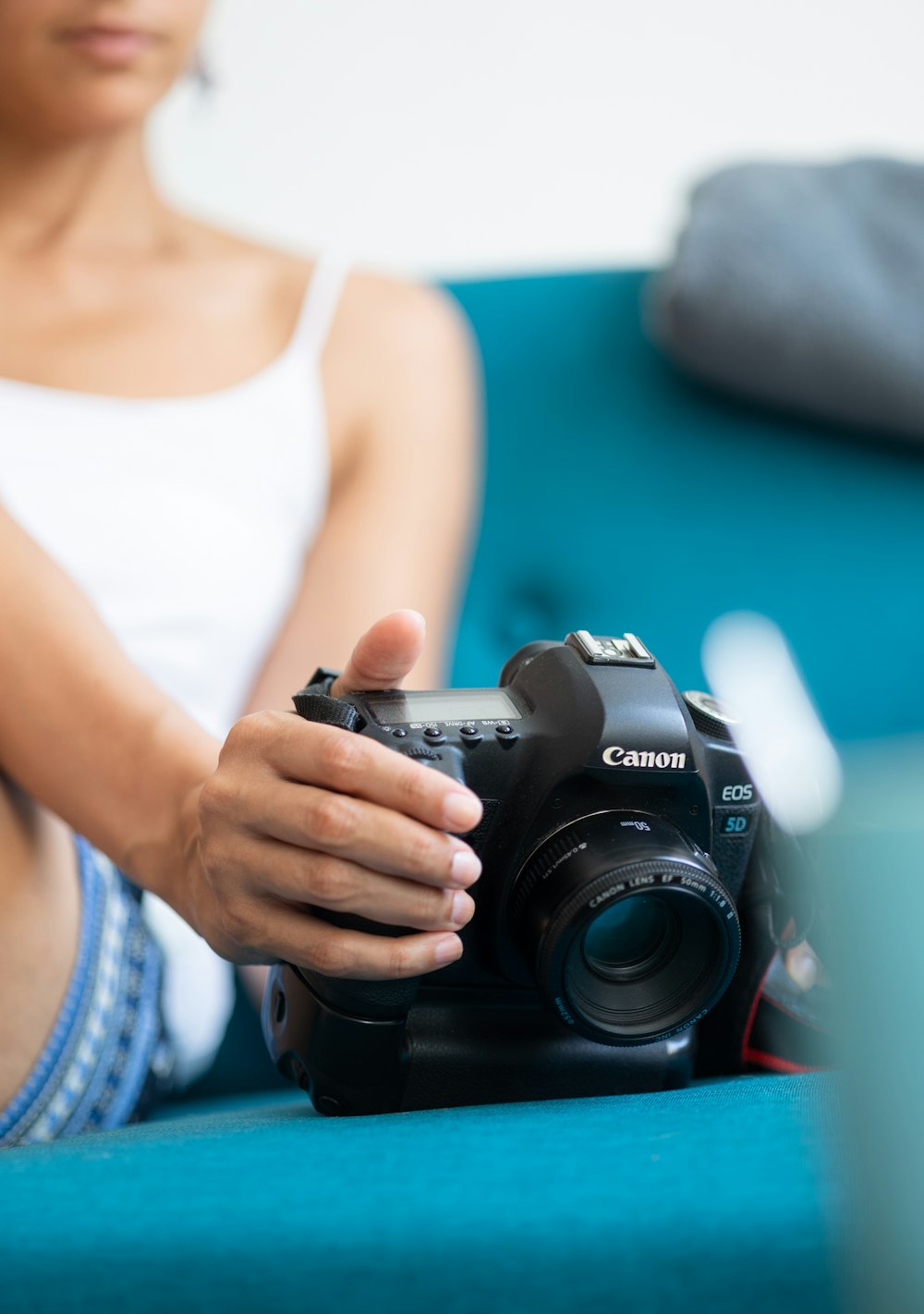 woman in white tank top holding black nikon dslr camera