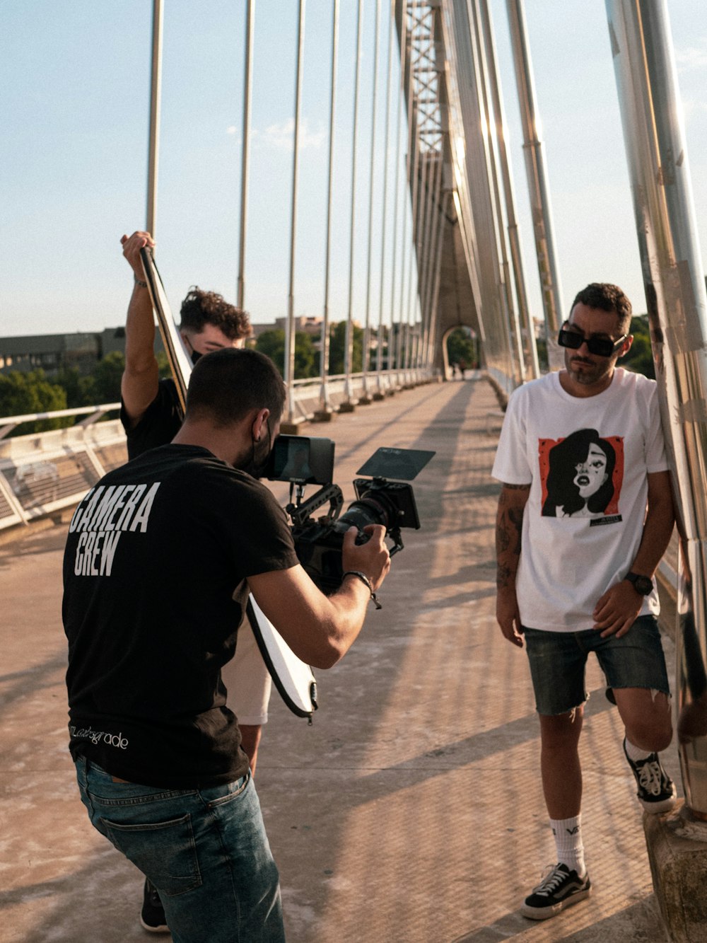 Uomo in t-shirt girocollo bianca e nera e pantaloncini di jeans blu con DSLR nera