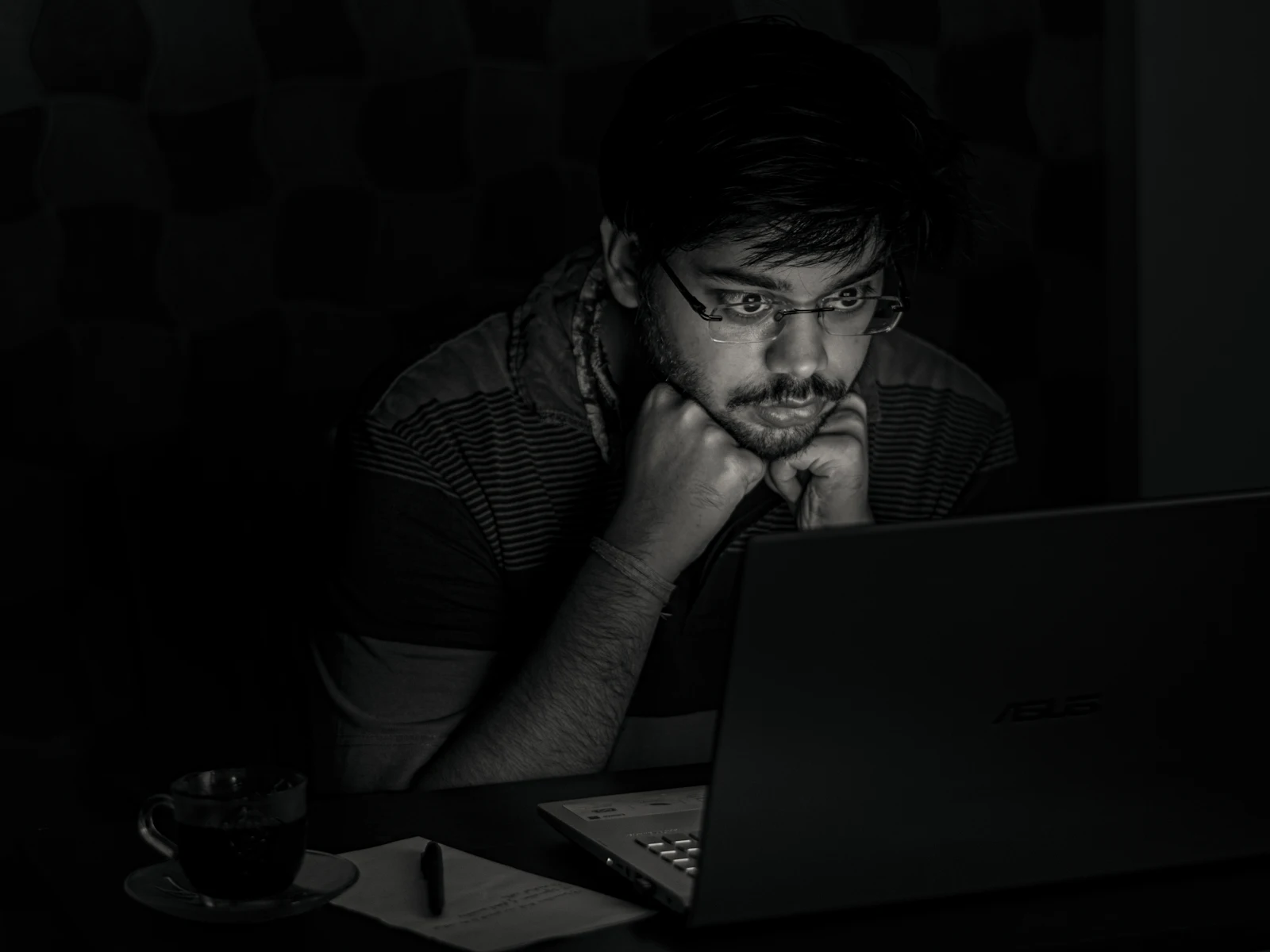 A young Indian man working on a laptop and monitor