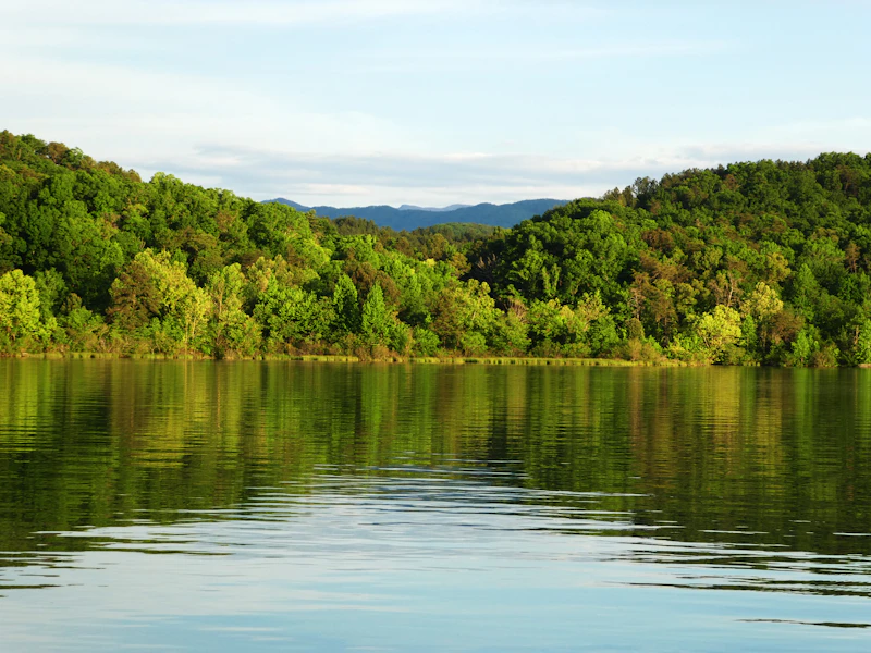 Colorful autumn trees reflecting in a calm Tennessee lake with forested ridges behind