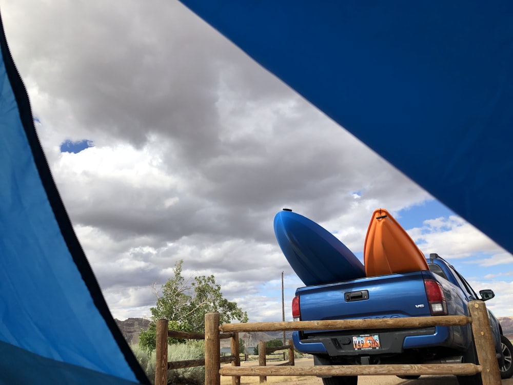 black chevrolet car parked on brown wooden fence under white clouds and blue sky during daytime