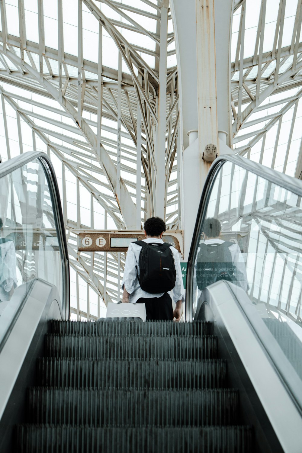 man in black jacket and blue denim jeans standing on escalator