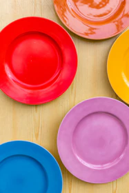 Close-up of colorful ceramic plates with textured surfaces on a rustic table.