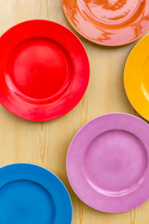 A set of colorful ceramic plates stacked on a rustic wooden table.