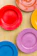 A stack of colorful paper plates arranged neatly on a wooden picnic table.