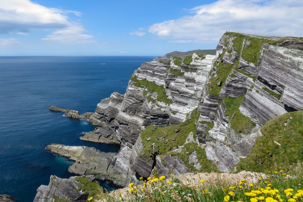 gray rocky mountain beside blue sea under blue sky during daytime