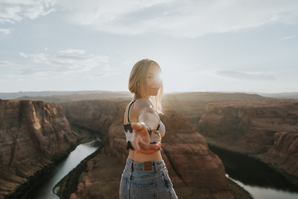 woman in blue denim shorts standing on cliff during daytime