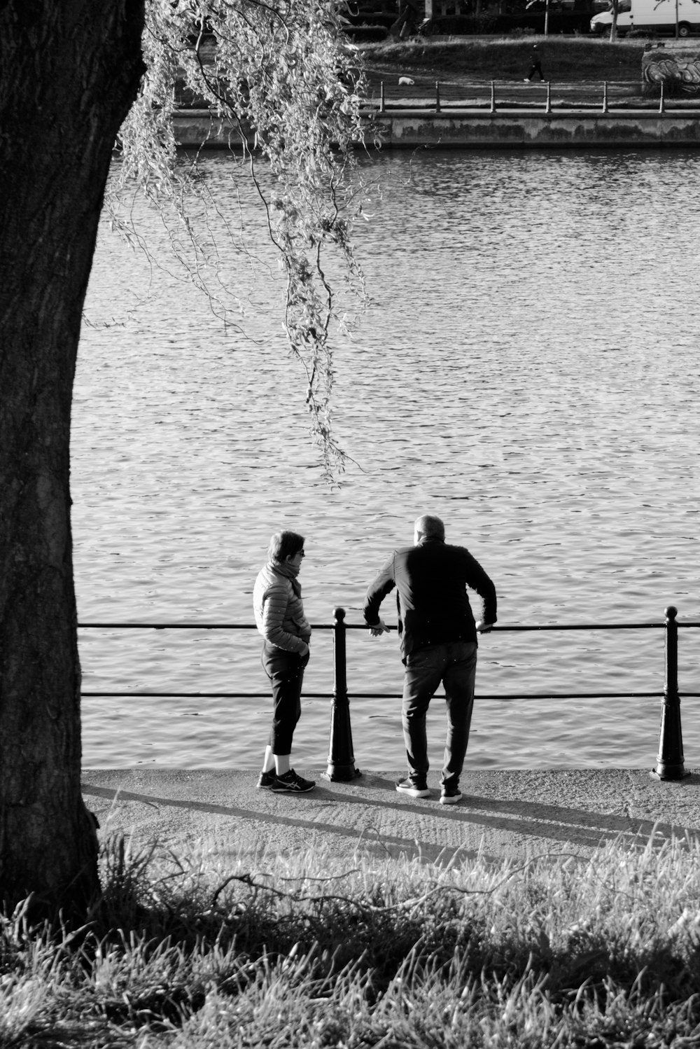 man and woman standing on dock near body of water during daytime