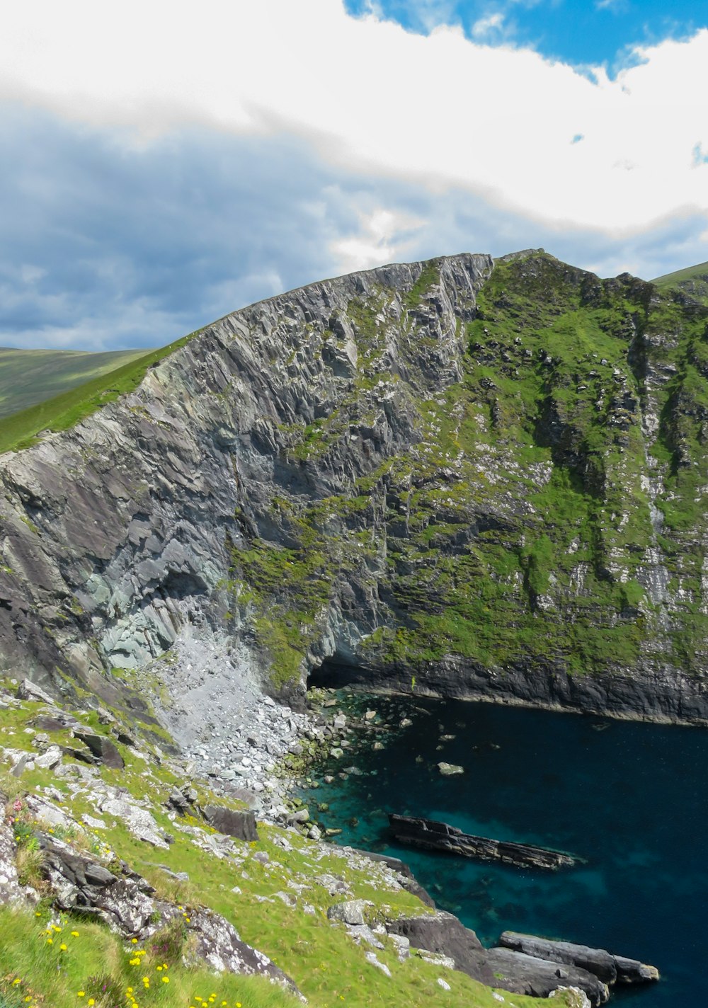 green and gray mountain beside body of water during daytime